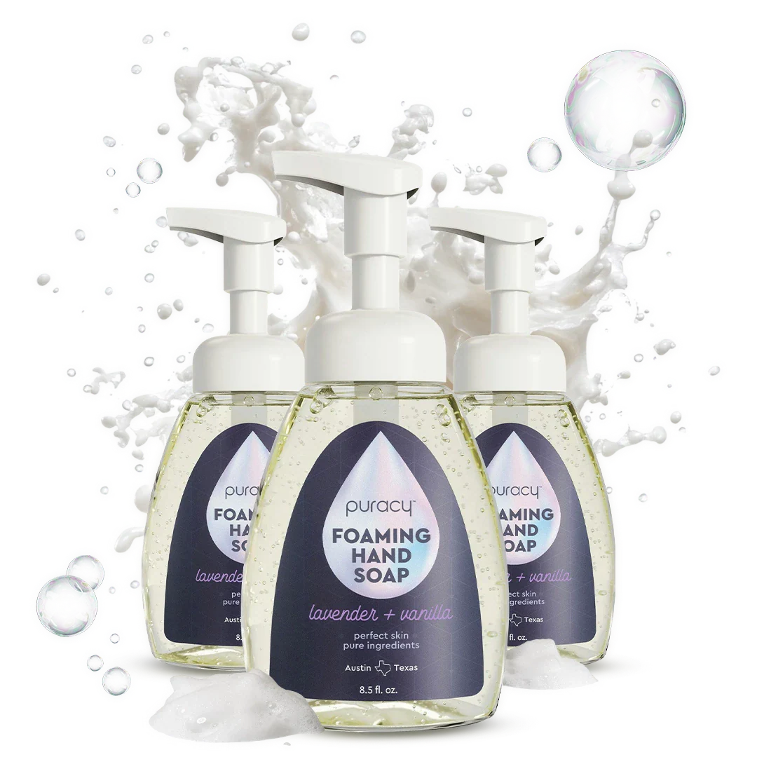 Three bottles of Puracy foaming hand soap with a splash of water on a white background
