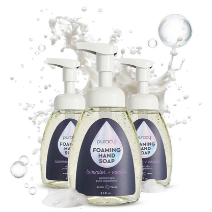 Three bottles of Puracy foaming hand soap with a splash of water on a white background